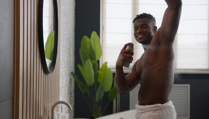 Man sprays his armpit with deodorant.